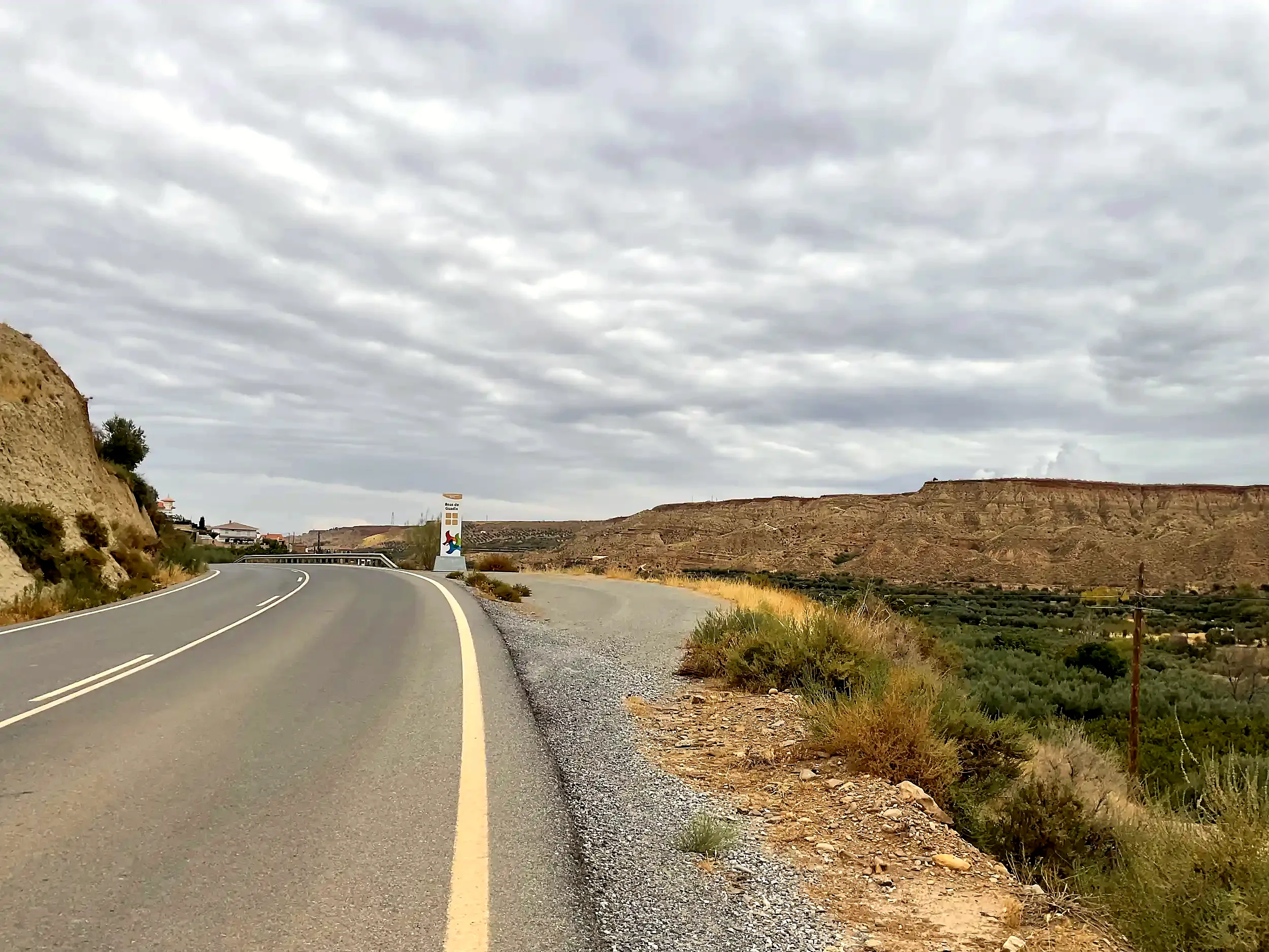 Carretera a la entrada de Beas, con el pueblo al fondo y el valle a la derecha